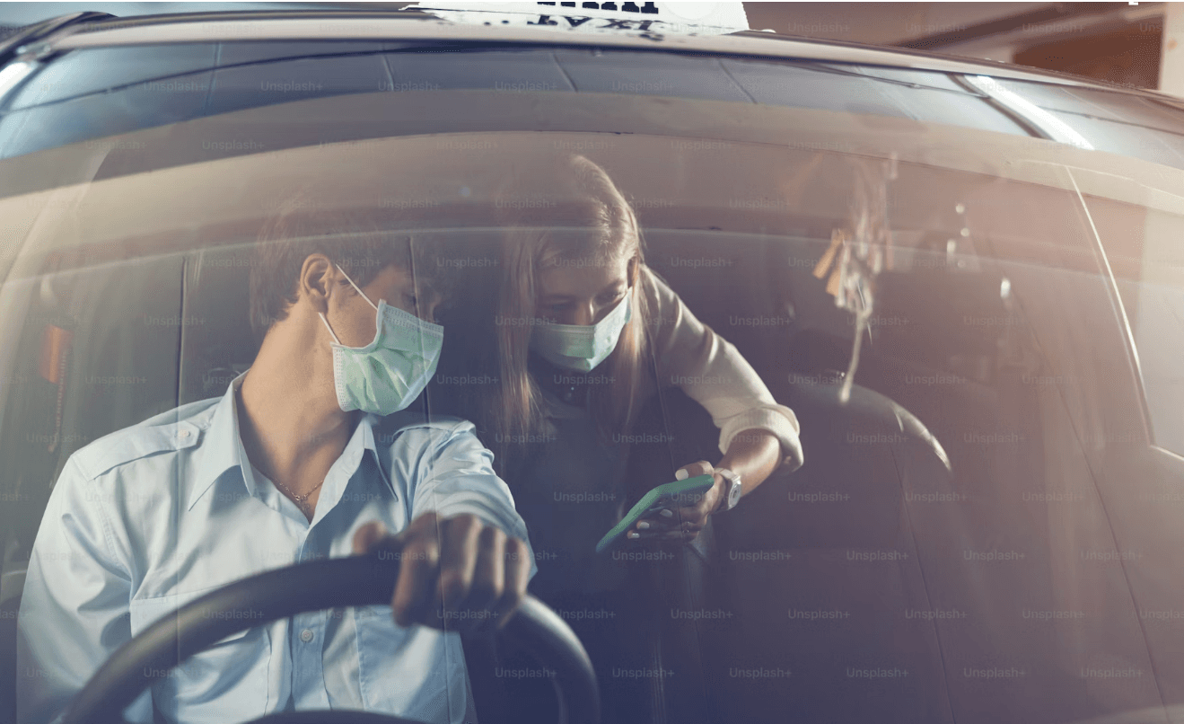 A driver handing an item to a passenger in a car